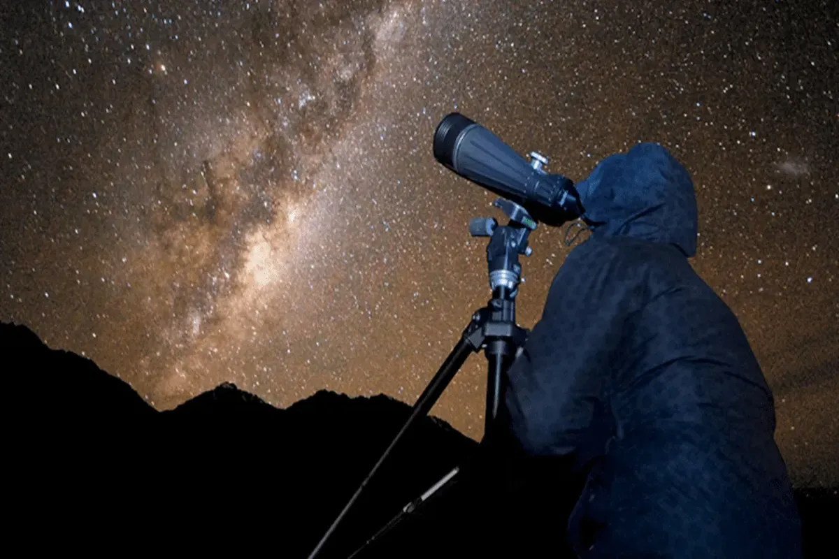 A telescope set up beside a Bedouin camp under the night sky